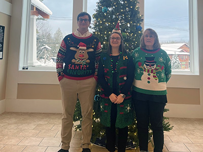 Three People Wearing Holiday Sweaters