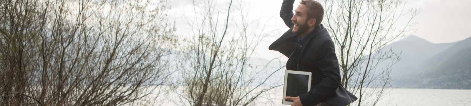 Man Jumping Outside Holding a Tablet