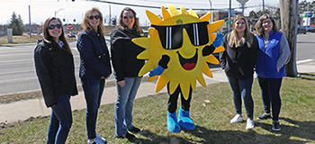 Five People Standing Next to a Sun Costume