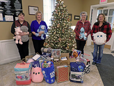 Four Women Holding Stuffed Animals Next to Toys