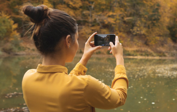 Girl Holding Cell Phone Taking a Picture in the Fall